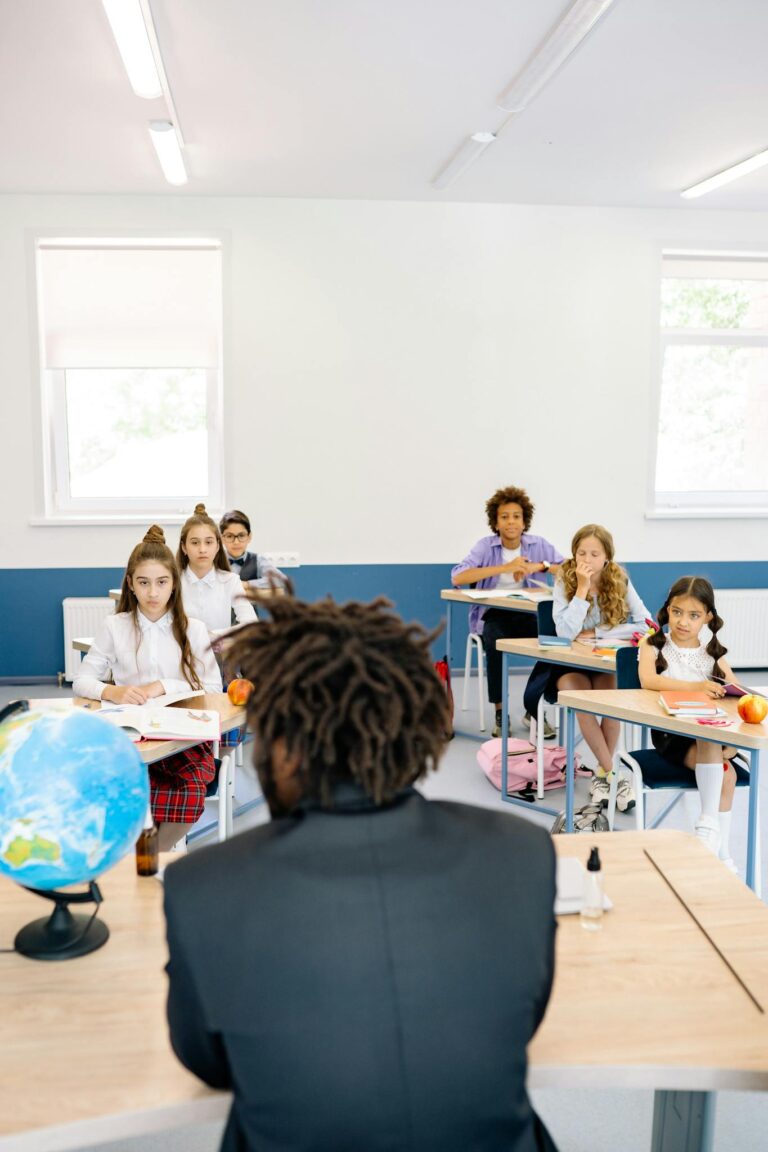 Teacher in classroom engaging with attentive students at desks.